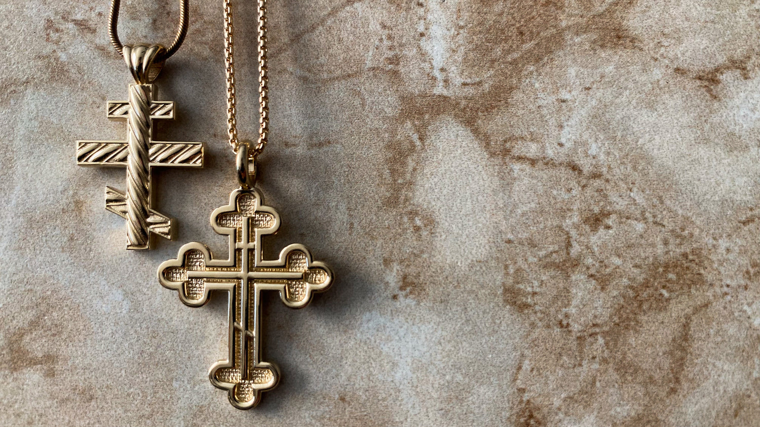 Gold cross pendants on a textured stone surface